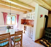 A kitchen in a cabin with a fireplace, view of the wooden ceiling and red curtains.