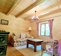 Interior of a cabin with wooden decor, a comfortable couch, and a tiled stove.