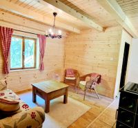 Living area in a cabin with a wooden decor floor, upholstered sofa, and wicker chairs.