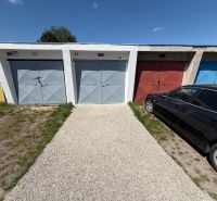 Garages on Bezručova Street in Trenčín with a car parked next to them on the grass.