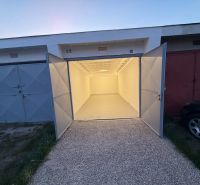 Open garages on Bezručova Street in Trenčín with concrete floors and white walls.