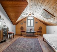 Attic room of a cottage with a wooden ceiling, antique furniture, and a floor with a wooden decor.