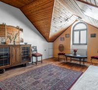 Attic with wooden paneling, antique furniture, wooden decor flooring, decorative carpet.