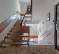 A cottage with a staircase with wooden slats and pictures on the walls.