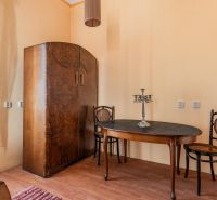 The interior of a cabin with wooden floor decor, an antique table, two chairs, and a wardrobe.