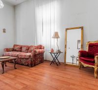 Living room in a cottage with a patterned sofa, mirror, and floor with wooden decor.