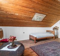 A cabin with a wooden floor decor, a bed, a carpet, and decorations.