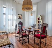 Dining room in a cottage with decorated chairs and a wooden-patterned floor.