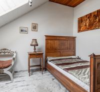 A room in a cottage with antique wooden furniture, a floor with a wooden decor, and a sloped ceiling.