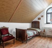 A room in a cottage with wooden decor, antique furniture, a bed by the window.