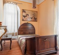 A room in a cottage with a bed, a mirror, a painting, and a floor with a wooden decor.
