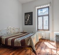 A bedroom in a cottage with a bed, a decorative dresser, and a floor with a wooden decor.