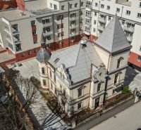 A historical building surrounded by modern apartment buildings on Hviezdoslavova Street in Trenčianske Teplice.