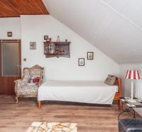 Interior of a cottage with a wooden decor floor, an armchair, and decorations on the wall.