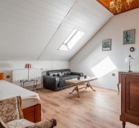 A room in a cottage with a wooden floor, a sofa, and antique furniture.