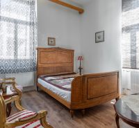 A bedroom in a cabin with wooden furniture, patterned curtains, and a floor with a wooden design.