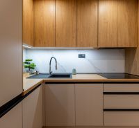 A kitchen in a 2-room apartment with a wooden decor floor and built-in appliances.