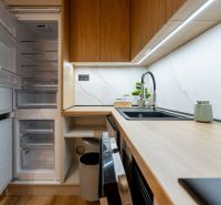 A kitchen in a 2-room apartment with a wooden decor floor and built-in appliances.