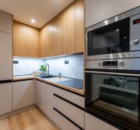 A kitchen in a 2-room apartment with a wood-patterned floor and built-in appliances.