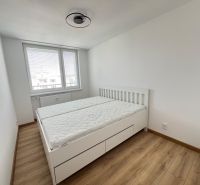 A bedroom with a bed, mattresses, and a wooden decor floor in a two-room apartment.