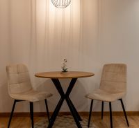 Dining nook in a two-room apartment with a wood-patterned floor and a round table.