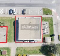 A building with commercial spaces and a parking lot in Žiar nad Hronom at the intersection of streets.
