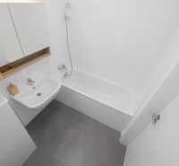 A bathroom in a 2-room apartment with a bathtub, sink, and mirrored cabinet.