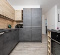 A kitchen in a 2-room apartment with a wooden decor floor and a modern gray kitchen unit.