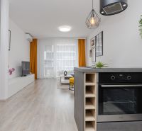 Kitchen with living room in a 2-room apartment, wooden decor flooring, yellow curtains.