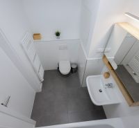 Bathroom with a mirror, sink, toilet, and ladder radiator in a 2-room apartment.