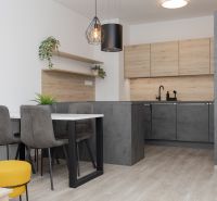 A kitchen with dark furniture, a table with gray chairs, and a floor with a wooden decor.