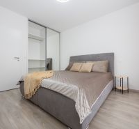 Bedroom in a 2-room apartment with a bed, wardrobe, and floor with a wooden decor.