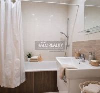 Bathroom with a bathtub, sink, and laundry basket in a studio apartment.