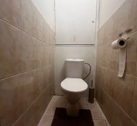A toilet with light tiles in a 2-room apartment.