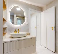 A bathroom in a 3-room apartment with an elegant illuminated mirror and storage spaces.