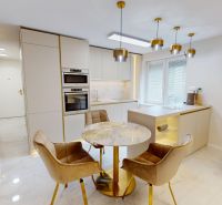 A kitchen space in a 3-room apartment with a marble table and golden chairs.