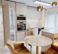 Dining area with a round table and golden lights in a 3-room apartment.