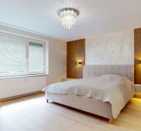 Bedroom with a mirror, chandeliers, and a bed in a 3-room apartment, floor with wooden decor.