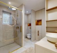 The interior of a bathroom in a 3-room apartment with a spacious shower and gold accessories.
