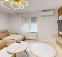 Living room with a sofa and a television in a three-room apartment, floor with wooden decor.