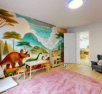 Children's room in a 3-room apartment with a dinosaur mural and wooden decor flooring.