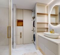 A bathroom in a 3-room apartment with a sink, shower, and a washer with a dryer.
