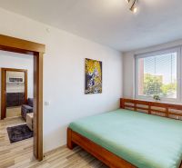 A bedroom in a three-room apartment with a wooden decor floor and large windows.