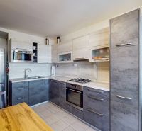 A kitchen in a 3-room apartment with a kitchen unit, table, and floral decoration.