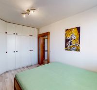 A bedroom with white furniture, a picture of a leopard, a television, and a wooden decor floor.