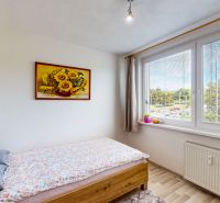 A bright room with a bed and a painting of sunflowers in a 3-room apartment.