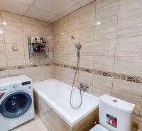 Bathroom in a 3-room apartment with a bathtub, washing machine, and toilet, in ceramic tiles.