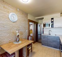A kitchen with stone cladding, a wooden table, and a modern kitchen unit in a 3-room apartment.