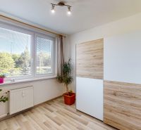 A room in a 3-room apartment with a large window, a wardrobe, and a floor with a wooden decor.