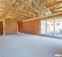 Unfinished interior with exposed ceiling and large windows in a family house.